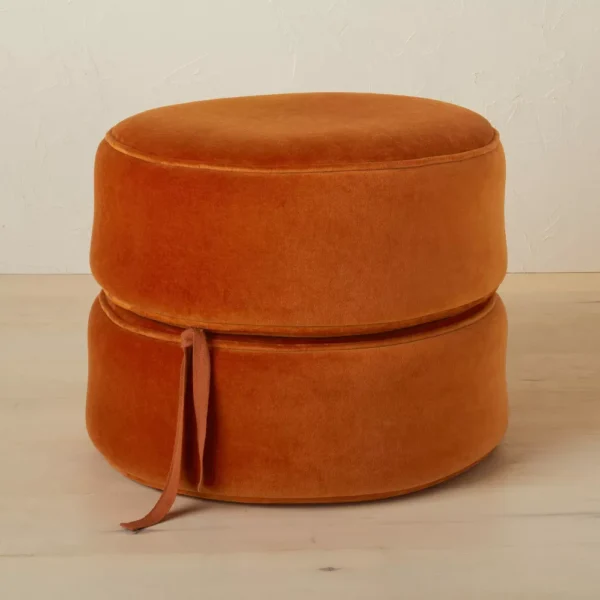 round pouf upholstered footrest Rust-colored round pouf ottoman with upholstered fabric and stackable cushion layers